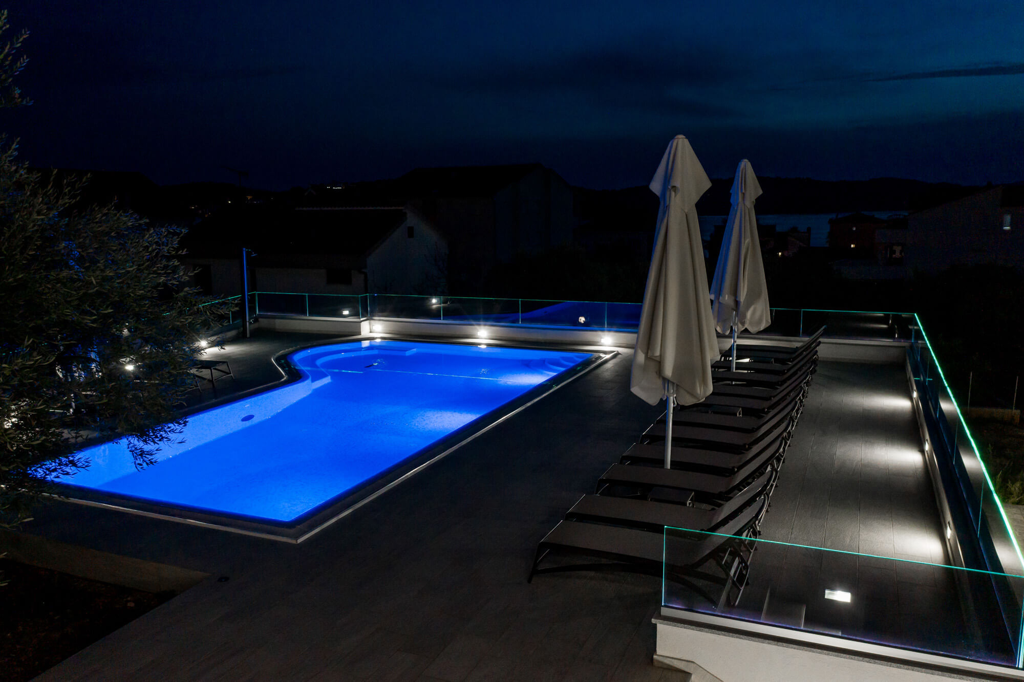 pool, pool deck and lounge chairs at night time