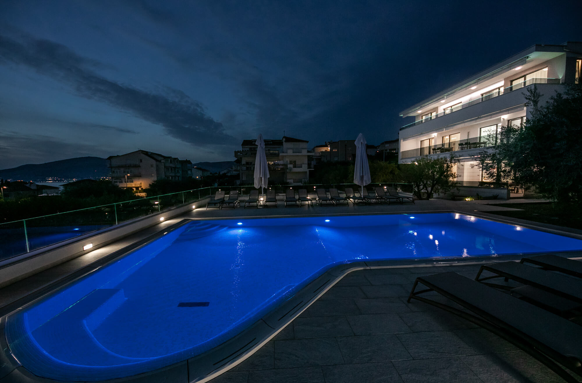 pool, pool deck, lounge chairs and house at night time